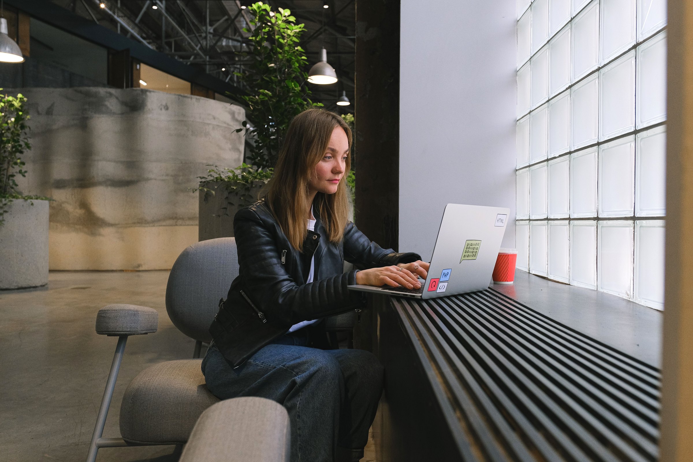 Professional working on a laptop at a counter in a modern glass-walled workspace